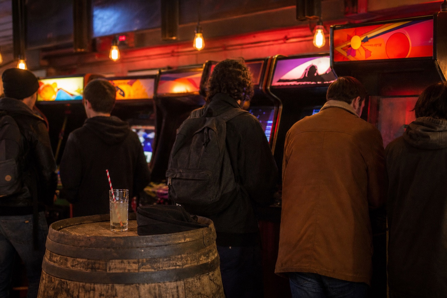 Intérieur de bar à bornes d'arcade un samedi soir, rangée de bornes aux marquee colorés sous des ampoules chaudes